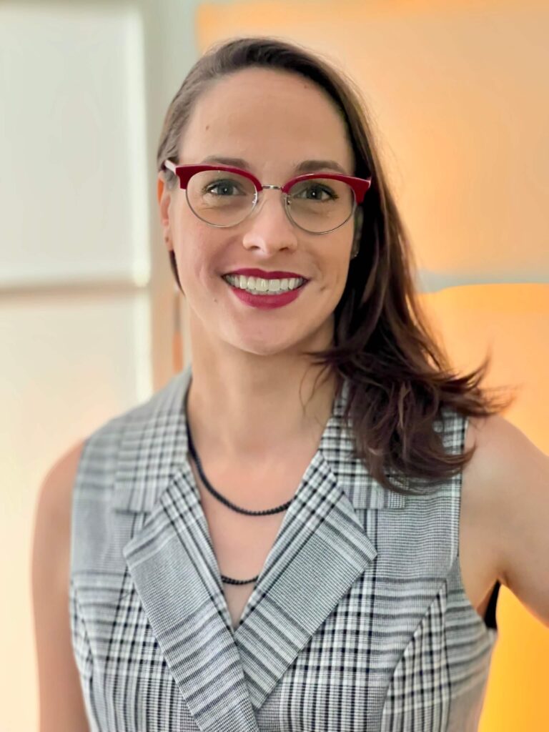Jenna Owsianik headshot shows a white woman with red glasses and brown hair.